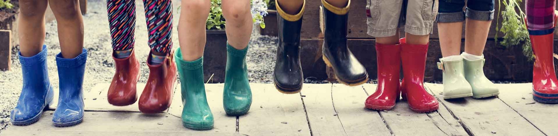 Many children having fun jumping in their brightly colored rainboots.