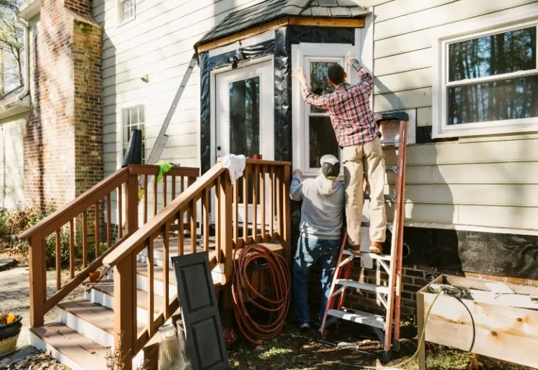 Construction workers repairing the siding of a house during the fall season