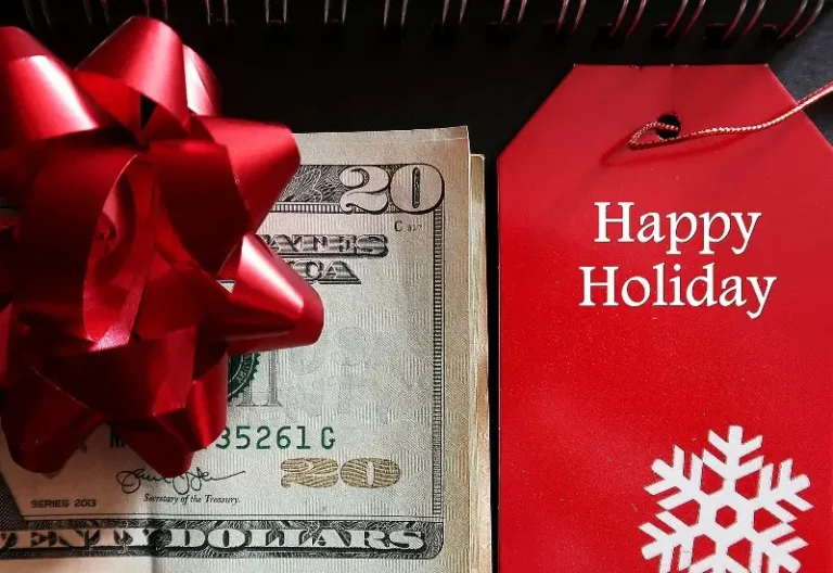 Red bow sitting on cash next to a Happy Holidays card