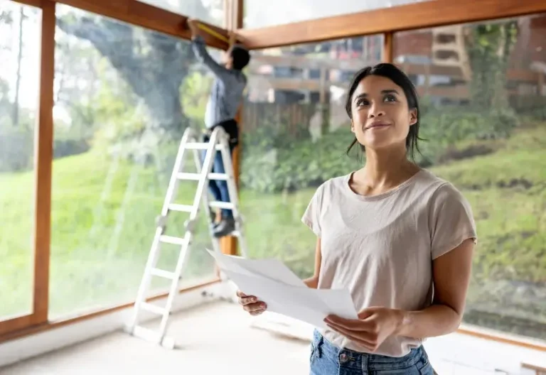 Woman holding home renovation designs while standing on construction site