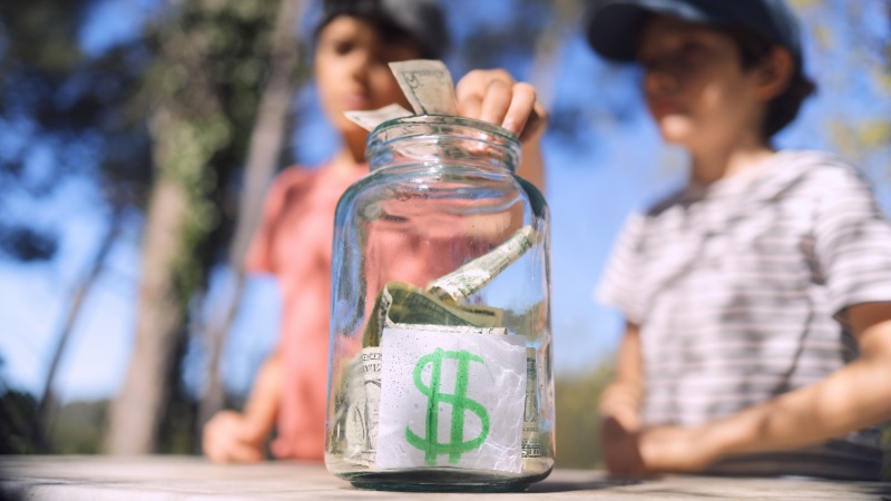 Children placing money into a savings jar